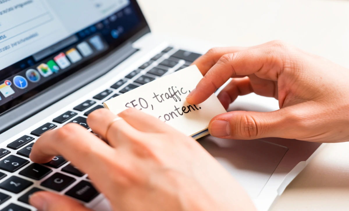 Person typing on a laptop while comparing SEO blogging tools and platforms